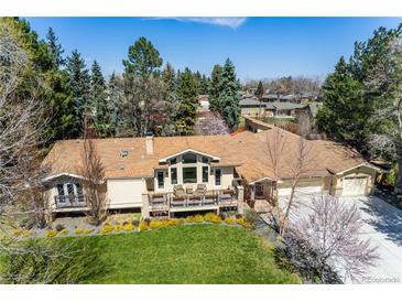 Stunning home featuring mature trees, lush landscaping, and a spacious deck perfect for outdoor living at 10395 W 74Th Pl, Arvada, CO 80005
