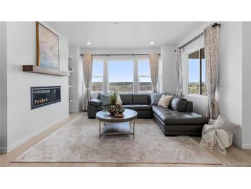 Bright living room featuring a fireplace, large windows, and a comfortable sectional sofa at 13446 Amber Sky St, Parker, CO 80134