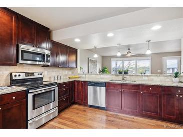 A kitchen featuring stainless appliances, granite countertops and dark wood cabinets at 1095 W 69Th Ave, Denver, CO 80221