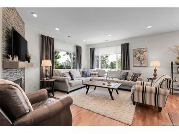 Bright living room features hardwood floors, fireplace, and large windows with backyard views at 10152 Bluffmont Ln, Lone Tree, CO 80124