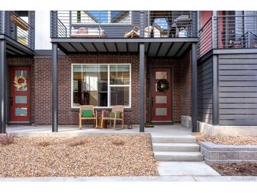 Inviting front porch with brick facade, rocking chairs, and stylish red door, offering a cozy curb appeal at 12193 W 51St Ave, Wheat Ridge, CO 80033