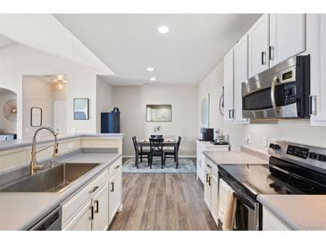 Bright kitchen boasts stainless appliances, white cabinets, and an adjacent dining area with wood floors at 1575 Olympia Cir # 303, Castle Rock, CO 80104