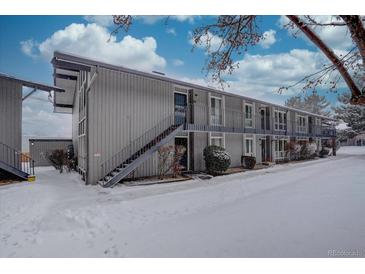 Gray condo building exterior with snowy landscaping at 6495 E Happy Canyon Rd # 88, Denver, CO 80237