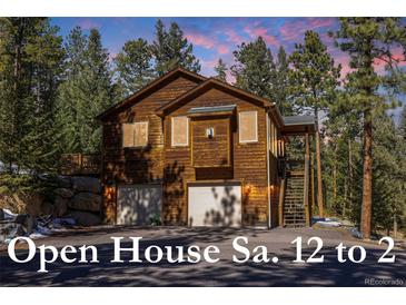 Charming two-story brown home with two-car garage nestled among mature evergreen trees at 6752 S Columbine Rd, Evergreen, CO 80439