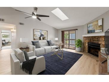 Bright living room features a stone fireplace, ceiling fan, skylight, and sliding glass doors at 8600 E Alameda Ave # 22-208, Denver, CO 80247