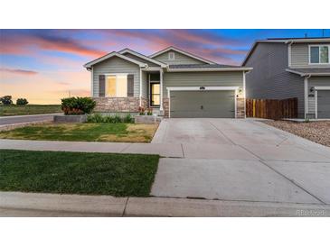 Charming home featuring a well-manicured lawn and a beautiful stone-accented facade, set against a vibrant sunset at 581 Park Blvd, Brighton, CO 80603