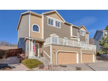 Tan and brown two-story townhouse with attached garages and a charming front porch at 2673 Live Oak Ct, Castle Rock, CO 80104