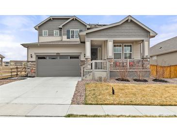 Charming two-story home with a gray exterior, stone accents, a well-kept lawn and a welcoming front porch at 17614 Drake St, Broomfield, CO 80023