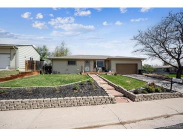 Charming single-story home featuring a well-maintained lawn and inviting curb appeal with a brick retaining wall and landscaping at 9508 Lou Dr, Northglenn, CO 80260