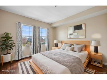 Bright bedroom featuring two windows, hardwood floors, and a comfortable queen size bed at 975 N Lincoln St # 10A, Denver, CO 80203