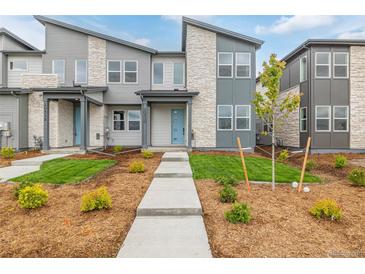 Beautiful townhome with modern exterior, stone accents, a landscaped yard, and concrete walkway at 20530 E 58Th Ave, Aurora, CO 80019