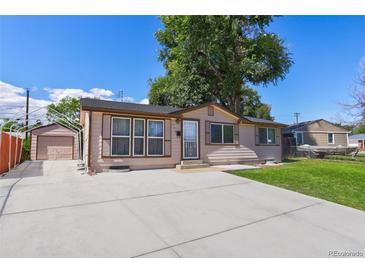 Charming single-story home with a well-manicured lawn, long concrete driveway, and an attached garage in the back at 7391 Dale Ct, Westminster, CO 80030