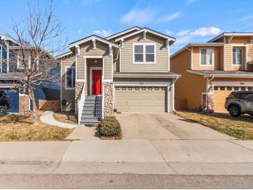Charming two-story home featuring a red front door, attached garage, and stone accents at 3155 Kedleston Ave, Highlands Ranch, CO 80126