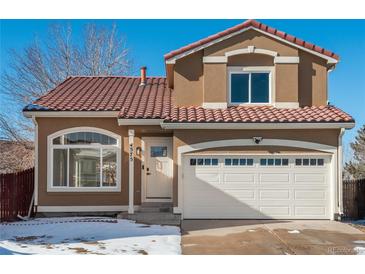 Two-story house with a brown exterior, red tile roof, and a white garage door at 4575 Gibraltar St, Denver, CO 80249