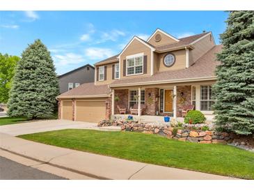Inviting home with a manicured lawn, brick accents, and a charming front porch with chairs at 2359 Indian Paintbrush Cir, Highlands Ranch, CO 80129