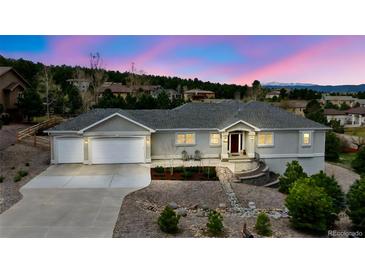 Charming home featuring a two-car garage, landscaped front yard, and inviting entrance under a beautiful evening sky at 1553 Plowman Dr, Monument, CO 80132