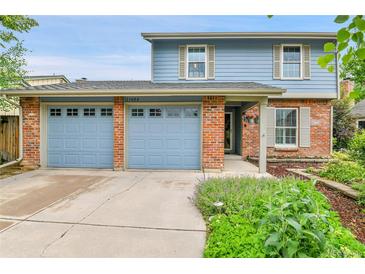 Charming blue two-story home with a brick facade and a two car garage at 11404 W Sharkstooth Peak, Littleton, CO 80127