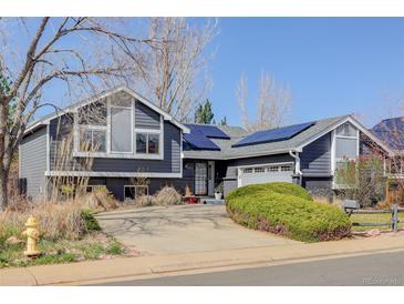 Charming home with solar panels, gray siding, brick accents, mature landscaping, and a spacious driveway at 1413 Ben Nevis Ave, Broomfield, CO 80020