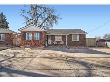 Charming brick home featuring a large driveway and classic design elements under a clear blue sky at 7070 W 39Th Ave, Wheat Ridge, CO 80033