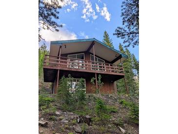 Rustic home with a spacious balcony, nestled amongst lush trees and foliage at 542 Harris Dr, Idaho Springs, CO 80452