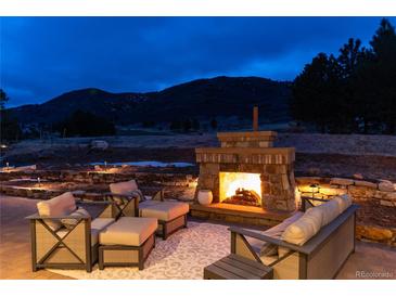 A scenic outdoor patio featuring a stone fireplace, cozy seating and picturesque views at 8033 Galileo Way, Littleton, CO 80125