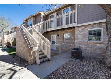 Brick exterior with stairs to the second level and river rock landscaping with trees in the foreground at 2716 E Otero Pl # 6, Centennial, CO 80122