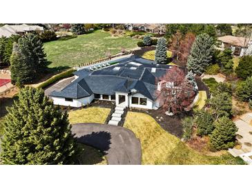 Stunning aerial view of modern home with manicured landscaping, a dark roof, and beautiful trees at 49 Charlou Cir, Cherry Hills Village, CO 80111