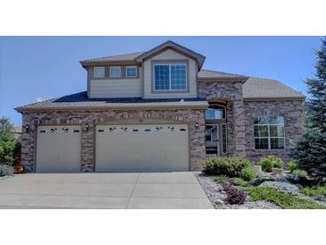 Two-story brick home featuring a large two car garage, manicured yard, and charming architectural details at 973 Orion Way, Castle Rock, CO 80108