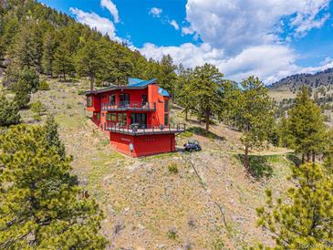 Stunning red modern home nestled into the mountain, boasting balconies and breathtaking views at 5896 Peregrine Trl, Golden, CO 80403