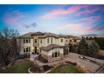 Stunning two-story stucco home boasting stone accents, manicured lawn, and a winding driveway leading to a two car garage at 12532 Daniels Gate Dr, Castle Pines, CO 80108