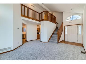 Bright living room with a staircase, high ceilings, and an open view of the kitchen at 11580 Depew Ct, Westminster, CO 80020