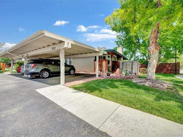 View of the carport with parking and landscaping with mature trees and well-maintained lawn at 8730 E Roundtree Ave, Greenwood Village, CO 80111