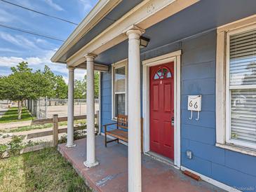 Charming front porch with white columns, a red front door and a bench provides a cozy entrance to the home at 66 E 45Th Ave, Denver, CO 80216