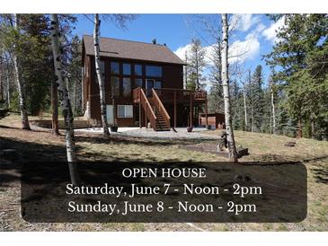 Charming exterior view of home with deck and stairs surrounded by forest and hosting an open house at 10438 Sunlight Ln, Conifer, CO 80433
