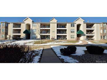 Tan three-story condo building with balconies and snow-covered landscaping at 12233 W Cross Dr # 204, Littleton, CO 80127