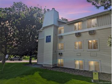 Low angle view of a tan apartment building on a green lawn, with trees and a dusk sky at 17361 E Mansfield Ave # 532R, Aurora, CO 80013