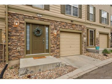 Tan three-story townhome with stone accents, attached garage, and landscaping at 985 Burning Bush Pt, Monument, CO 80132