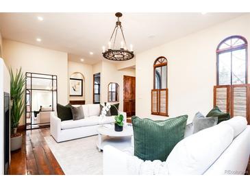 Bright living room with hardwood floors, white sofas, decorative chandelier and arched windows with wooden shutters at 2435 S Milwaukee St, Denver, CO 80210