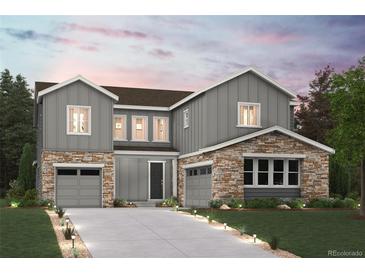 Striking two-story home with stone accents, a well-manicured lawn, and gray siding at 13765 Emerald Lake St, Parker, CO 80138