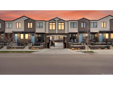 Modern townhomes featuring brick facade, blue doors, and manicured landscaping at 5469 S Curtice St # E, Littleton, CO 80120