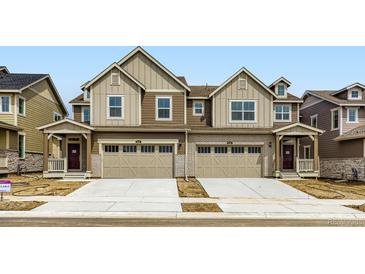 Modern townhome with beige and brown siding, a two-car garage, and a small front porch at 6751 Arbor E Blvd, Thornton, CO 80602