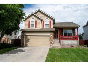 Charming home with two-car garage, covered front porch, red shutters, and a well-manicured lawn at 10534 Ursula St, Commerce City, CO 80022