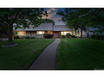Charming single-story home with mature trees, lush green lawn and inviting walkway at 2250 N Monaco Pkwy, Denver, CO 80207