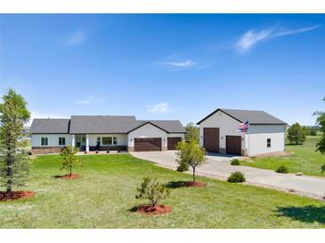 A bright ranch-style home with a large garage, a long driveway, and a well-manicured front lawn at 3047 Deer Creek Ranch Loop, Parker, CO 80138
