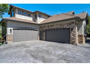 A spacious three-car garage featuring stone accents and ample parking space at 24031 E Hinsdale Pl, Aurora, CO 80016