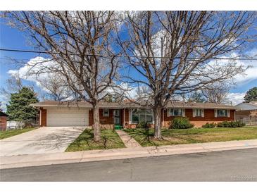 Charming single-story red brick home with mature trees, a lush lawn and an attached two-car garage at 2081 W Ridge Rd, Littleton, CO 80120