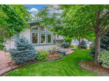 Landscaped front yard with mature trees, flowering shrubs, and manicured lawn at 1080 Tantra Park Cir, Boulder, CO 80305