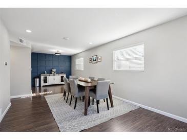 Bright dining area with wood floors, large windows, and a stylish accent wall at 962 Uvalda St, Aurora, CO 80011