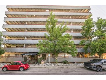 Multi-story apartment building with a lush green tree in front and two cars parked on the street at 1441 N Humboldt St # 504, Denver, CO 80218