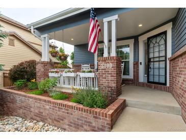 Inviting front porch with brick columns, flower boxes, and rocking chairs at 3100 Rockbridge Dr, Highlands Ranch, CO 80129